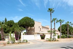 a house with palm trees in front of a street at Apartamento Sancti Petri in Chiclana de la Frontera