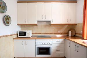 a kitchen with white cabinets and a stove and a microwave at Apartamento Sancti Petri in Chiclana de la Frontera