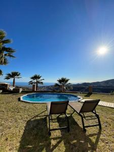 a couple of chairs sitting next to a swimming pool at Casa Helen in Torrox