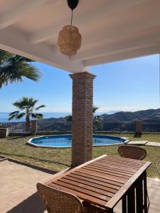 a patio with a table and chairs and a pool at Casa Helen in Torrox