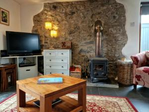 ein Wohnzimmer mit einem Tisch und einem Holzofen in der Unterkunft LYDONIA BARN in Lydford
