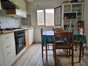 a kitchen with a table and some chairs and a kitchen with a stove at Charmant chalet 200 m de la mer in Merville-Franceville-Plage