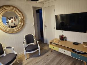 sala de estar con mesa, sillas y espejo en Charmant chalet 200 m de la mer en Merville-Franceville-Plage