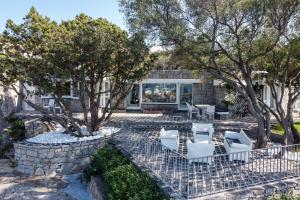 eine Terrasse mit weißen Stühlen und Bäumen vor einem Gebäude in der Unterkunft Villa Cava Del Tom Luxury in Porto Rotondo