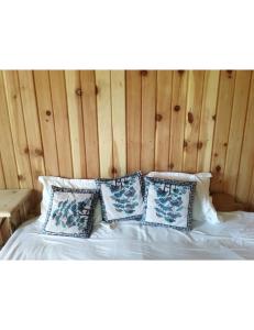 a bed with four pillows and a wooden wall at Hotel Mountain View, Chakrata in Chakrāta