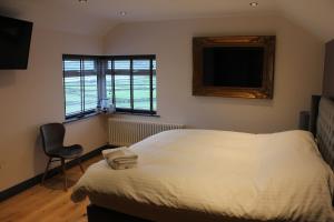 a bedroom with a bed and a chair and a television at The Boshaw Trout in Holmfirth