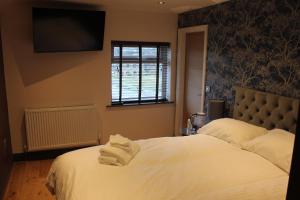 um quarto com uma cama e uma televisão na parede em The Boshaw Trout em Holmfirth