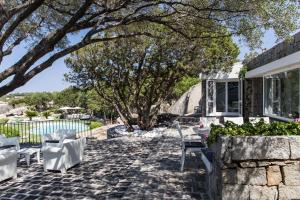 eine Terrasse mit weißen Stühlen und einem Baum in der Unterkunft Villa Cava Del Tom Luxury in Porto Rotondo