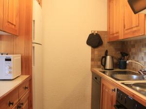 eine Küche mit Holzschränken, einer Spüle und einer Mikrowelle in der Unterkunft Apartment Topaze 4 by Interhome in Villars-sur-Ollon