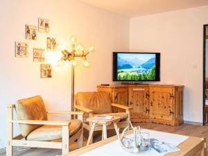 a living room with two chairs and a flat screen tv at Apartment Chesa Clüs 6 by Interhome in Zuoz