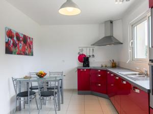 una cocina con armarios rojos y una mesa con sillas. en Holiday Home Va Zi Bihan - GUI111 by Interhome en Guissény