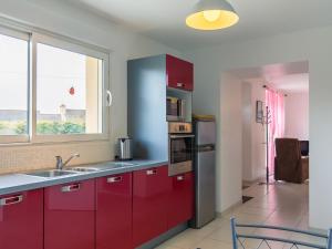 eine Küche mit roten Schränken und einem großen Fenster in der Unterkunft Holiday Home Va Zi Bihan - GUI111 by Interhome in Guissény
