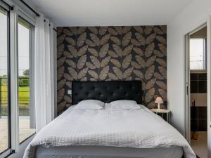 a bedroom with a bed and a wall with a leaf pattern at Holiday Home Kernic Ty - PLC219 by Interhome in Plounévez-Lochrist