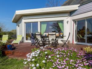 um deque com mesa, cadeiras e flores em Holiday Home Villa Panorama Mer by Interhome em Plounéour-Trez