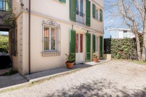 a house with green shuttered windows and potted plants at Villa Romantica Wellness & SPA in Lucca
