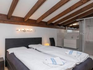 a bedroom with a large bed with white sheets at Chalet Le Fontany by Interhome in Randogne