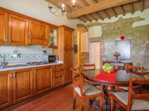 una cucina con armadi in legno e un tavolo con frutta di Apartment Fattoria Petraglia - Loggiato by Interhome a Monteriggioni