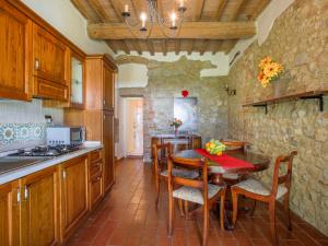 una cucina con tavolo e sedie e una cucina con parete in pietra di Apartment Fattoria Petraglia - Loggiato by Interhome a Monteriggioni