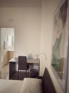 a bedroom with a desk with a chair and a bathroom at DOMOBLU Camere In Centro in Tortolì
