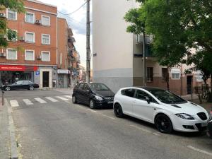 dos autos blancos estacionados al lado de una calle en Apartamento Vallecas Plaza, en Madrid