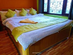 Una cama con sábanas amarillas y blancas y una ventana en Hotel Butterfly , Sauraha , Chitwan, en Sauraha