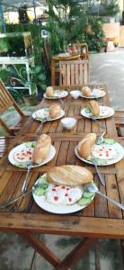 una mesa de madera con platos de sándwiches. en Tuyết Hoa Hòn Bồ Homestay en Da Lat