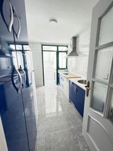 una cocina con armarios azules y una ventana y una puerta en Apartamento GUADALQUIVIR, en Sanlúcar de Barrameda