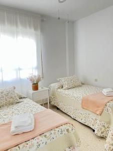 サンルーカル・デ・バラメダにあるApartamento GUADALQUIVIRのベッドルーム1室(ベッド2台、窓付)