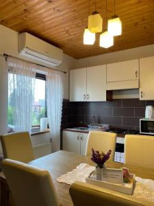 eine Küche mit einem Tisch und Stühlen sowie eine Küche mit weißen Schränken in der Unterkunft House Leonarda in Grabovac