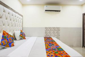 Zimmer mit einem weißen Bett und bunten Kissen in der Unterkunft FabHotel Welcome in Kānpur