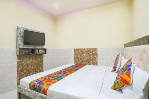 a bedroom with a bed with a tv on the wall at FabHotel Welcome in Kānpur