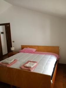 duże łóżko z drewnianą ramą w pokoju w obiekcie APP Angela - Ardaro 2 w mieście Riva del Garda