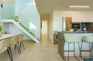a kitchen with white cabinets and a bar with stools at Luxury Duplex Penthouse Denia in Denia