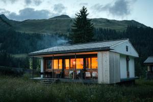 een klein huis in een veld met de lichten aan bij Chalet Horn in Davos Wolfgang