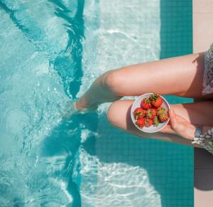 a person holding a bowl of strawberries in a swimming pool at Sun City Luxury Apartments in Asgourou