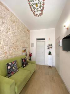 sala de estar con sofá verde y pared de piedra en Casa Vacanze: Eureka en Ostuni