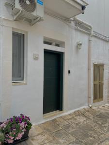 une porte de garage verte sur un bâtiment blanc orné de fleurs dans l'établissement Casa Vacanze: Eureka, à Ostuni