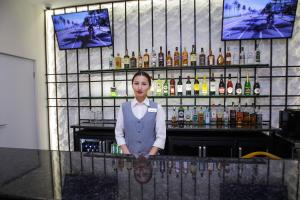 une femme se tenant derrière un bar avec des bouteilles d'alcool dans l'établissement Ardager Residence, à Atyraū