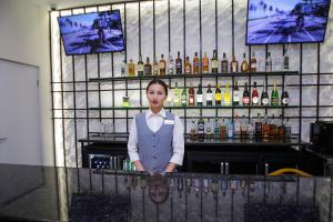 a woman standing behind a bar with bottles of alcohol at Ardager Residence in Atyrau