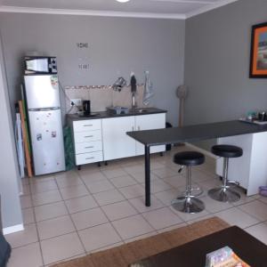 a kitchen with a table and two bar stools at 7 Diaz in Mossel Bay