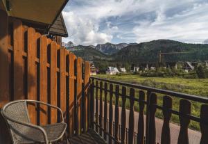 een stoel op een balkon met een hek en bergen bij Apartament Giewont-Tatra Home in Kościelisko