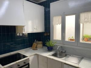 タマリウにあるLa mejor terraza de Tamariuの白いキャビネットとシンク付きのキッチン、窓2つが備わります。
