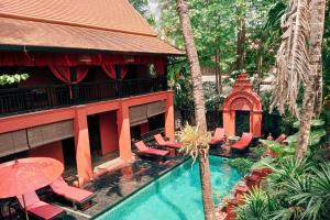 a resort with a swimming pool with chairs and an umbrella at Tri Yaan Na Ros Colonial House in Chiang Mai
