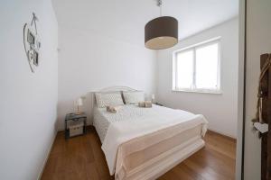 a white bedroom with a bed and a window at Appartamento Amaryllis, incantevole con piscina in Salò +11 photos