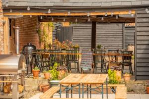 an outdoor patio with tables and chairs and a grill at The Firs Luxury Lodges and Glamping Tents in Cratfield