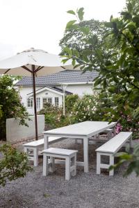 a picnic table and two benches with an umbrella at Vallby Cottage in Enköping