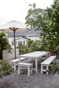 une table de pique-nique et deux bancs avec un parasol dans l'établissement Vallby Cottage, à Enköping