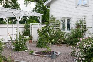 a garden in front of a white house at Vallby Cottage in Enköping