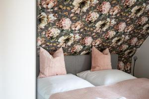 a bed with pink pillows and a floral wallpaper at Lieblingsplatz in Born