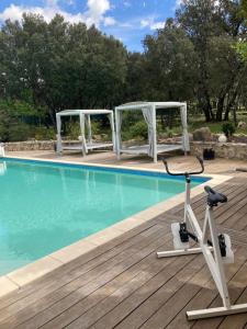 a swimming pool with a bike on a wooden deck at B&B Le Mas Des Chenes in Vacquières